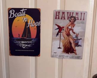Metal novelty signs including 'Boats n’ Hoes' and retro 'Hawaii' beach sign