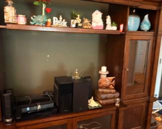 Large wooden entertainment center with glass cabinets and figurines