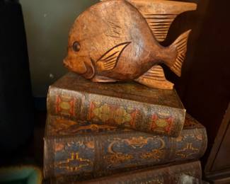 Carved wooden fish sculpture on stacked books