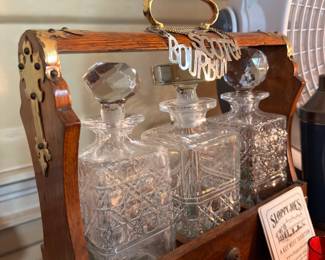 Cut glass decanter set with stoppers in wooden caddy labeled Bourbon