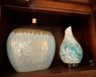 Decorative ceramic vases (cream relief and blue swirl) on wood shelf