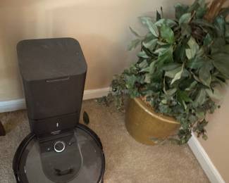 Robot vacuum base and potted artificial plant in gold planter
