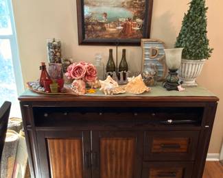 Wooden sideboard/buffet table with drawers and cabinets, decorated with framed art and greenery