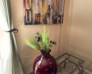 Glass-top coffee table with large red vase of greenery and floor lamp
