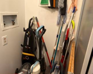 Closet containing upright vacuum cleaners, carpet shampooer, mops and brooms