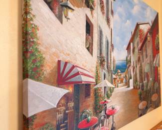 Framed wall art depicting European street scene with cafes and umbrellas