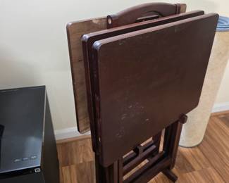 There are 4 dark stained TV trays and a stand.
