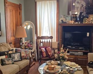 In the corner is a white wicker full length floor mirror.
