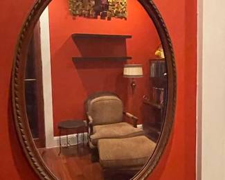 Oval mirror with wood and gilded frame, topped with a decorative floral crown. Measures 36" H x 24" W