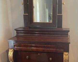 American Late Classical gilt and mahogany dressing bureau, second quarter 19th century. Conforming mirror frame and base detach from the bureau for moving purposes. Top drawer and two recessed drawers below. Decorative gilding on scroll columns and legs. Measures 88"H x 45"W x 21" D.