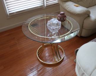 Glass top  lamp  table  with  brass  color stand.  It  is 27" in  diameter.