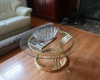Glass top  coffee table  with  brass stand.  It  is  36"  in  diameter.