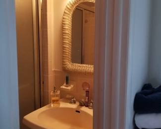 Pedestal sink; wicker mirror; vanity light