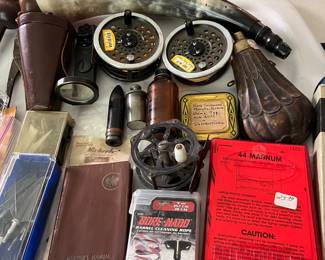 Many vintage hunting and fishing tools and accessories, including an antique powder flask; vintage fly reels; Nydar shotgun sight with case; numerous gun accessories, and more.