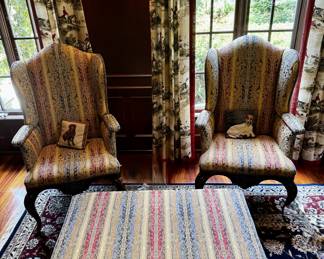 Two wing chairs with multi colored fabric, nailhead trim, and wood accents with matching upholstered ottoman