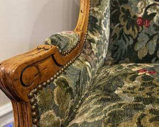 Detail of fabric, carved wood, and nail head design on the wing chair.