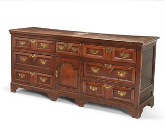 114
A George II Provincial oak low dresser
Mid-18th century
The rectangular top with molded edge fitted with seven drawers with later brass hardware surrounding a central enclosed cupboard, raised on bracket feet
33.5" H x 76" W x 20.5" D
Estimate: $2,000 - $3,000