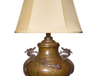 134
A Japanese bronze vase mounted as a lamp
Meiji Era (1868-1912), Circa 1890
The vase of bulbous form, with dragon figure handles to the sides, mounted as a single-light table lamp on a wood base with an oval fabric shade, electrified
Vase: 9.75" H x 14" Dia,; Shade: 12" H x 18.5" W x 14.25" D; Lamp without harp: 20.5" H
Estimate: $800 - $1,200