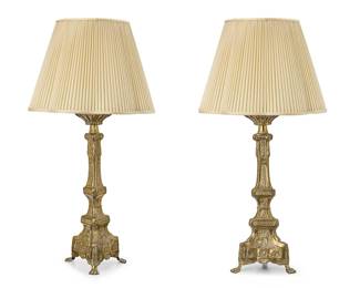 206
A pair of Continental brass candlestick lamps
19th century with later elements
Each with repoussé barley and grape motifs, raised on a tripartite base with paw feet, mounted as a single-light table lamp, surmounted by a pleated fabric shade, electrified
2 pieces
Each lamp without harp or shade: 22" H x 9" W.; Each shade: 12.75" H x 18.5" Dia.
Estimate: $400 - $600