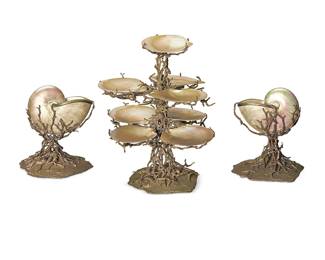 327
A Maitland-Smith silvered metal and shell table garniture
Late 20th century
The bases cast as branches of coral with sea stars and shells, comprising a metal-mounted scallop shell three-tier epergne and a pair of metal-mounted Nautilus shell vases
3 pieces
Epergne: 17" H x 14" Dia.; Each nautilus: 9.25" H x 8.25" Dia.
Estimate: $800 - $1,200