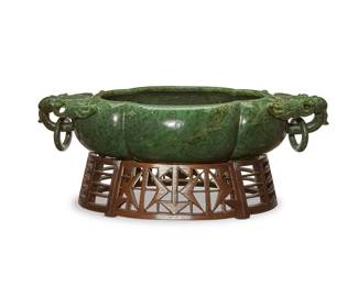 332
A Chinese carved green jade marriage bowl
20th century
Of lobed oblong form, with a carved bat and ring handle to each end, the interior carved with bats and Chinese characters, set on a pierced wood stand
Bowl: 5.25" H x 25" W x 12.5" D; Stand: 4.5" H x 17" W x 12.5" D
Estimate: $1,000 - $1,500