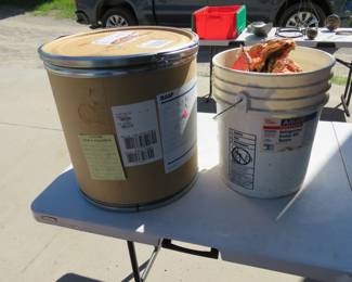 Lot 211. One-half a bag of charcoal in a bucket and a covered cardboard barrel