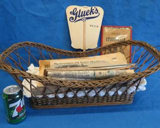 Lot 83. Antique wicker basket with an old Gluek's advertising fan, and Collector's Weekly and Antique monthly newspapers.