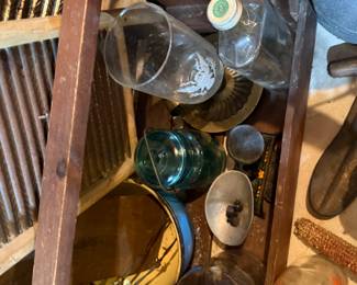 ooden washboard and a crate filled with antique glass bottles, jars, and other miscellaneous finds. Includes a green glass jug, a yellow-enameled pot, a small corncob, and various other collectible items.