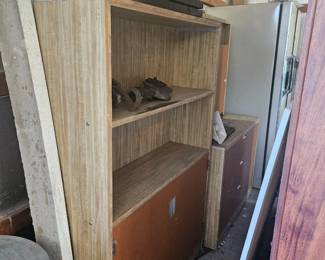Collection of wooden boards and shelving units leaning against a wall, including tall planks and cabinet components.