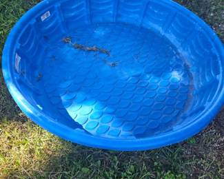 Blue round plastic kiddie pool or sandbox with textured bottom, set on grassy lawn.