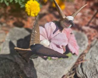 Whimsical garden statue depicting two snail-like creatures perched on a pink flower, cast in resin with a weathered finish.