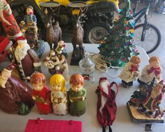 Grouping of vintage Christmas figurines such as wise men, angels, cherubs and decorated trees on display.