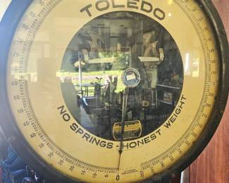 Close-up of a vintage Toledo scale dial reading 'No Springs – Honest Weight,' showcasing the detailed brass face and mechanism.