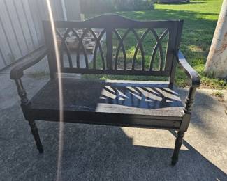 Outdoor metal and wood bench with decorative lattice backrest and curved arms.