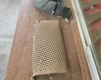 Vintage metal grater or rasp tool mounted on a wooden base.