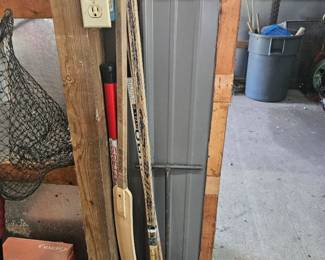 Tall grey storage container with two vintage wooden hockey sticks leaning against it.