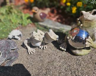 Whimsical garden figurine grouping: a large frog statue holding a shiny gazing ball alongside two small frogs in cloaks and a snail figure, perfect for outdoor decor.