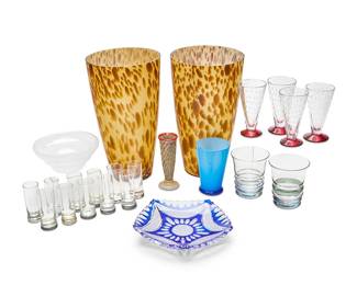 1303
A group of Modern glass table items
Late 20th/early 21st century
Bud vase marked: APQ
Comprising 11 vodka shot glasses from Saint Hilaire and various other makers, eight with silver-plated rim bases (3.5" H approx.), a set of 4 flared glasses with encased bubbles and ruby feet (5.25" H), a multicolored footed glass bud vase with a red lip (5.5" H), a cobalt cut-to-clear faceted glass dish (1.25" H x 9" Dia.), a Gorgeous Designs China blue and white cased glass tumbler (5" H x 3.5" Dia.), a Kosta Boda clam broth glass bowl (2.75" H x 6.25" Dia.), a pair of MT Vernon glass vases (12.75" H), and two associated tumblers
23 pieces
Estimate: $100 - $200