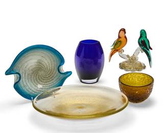 1120
A group of Contemporary art glass table items
20th/early 21st century
One signed and dated to underside: Michael Weems / 2005
Comprising a Murano green and orange bird figural group on a gold flecked glass base (7.5" H x 8" W x 4.5" D), a shallow bowl with gold flecks infused into the glass (2.5" H x 14.5" W x 11.5" D), a Murano blue and white cased glass bowl of swirl design with gold specks (2.75" H x 11.5" W x 9.75" D), a Michael Weems clear and frosted amber glass bowl (4" H x 6" Dia.), and a blue and clear glass vase (8.25" H)
5 pieces
Estimate: $150 - $250
