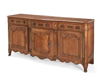 1177
A French Provincial carved oak enfilade
18th century
The serpentine front with three drawers above a locking single-door cabinet revealing a single shelf, and a locking two-door cabinet revealing two shelves, each interior later lined with moiré fabric
38" H x 74.5" W x 24" D
Estimate: $1,200 - $1,800