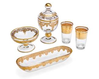 1069
A group of Continental gilt-decorated glass table items
20th century
Each juice embossed to underside: France
Comprising a footed bowl (3.5" H x 5" Dia.), a footed and lidded jar with ball finial (7.5" H x 4" Dia.), a pair of juice glasses (3.75" H x 2.25" Dia.), and an oblong molded glass tray (1.75" H x 9.5" W x 3.5" D)
5 pieces
Estimate: $100 - $200