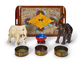 1317
A group of decorative table items
20th/early 21st century
Comprising a Brazilian inlaid wood handled serving tray, inset with butterfly wings beneath a piece of glass, two carved wood figures of elephants, three black and gilt japanned papier-mâché wine coasters, and a Chinese brass-mounted cinnabar and blue enameled bowl on a wood stand
7 pieces
Tray: 15.5" H x 24.5" W; Larger elephant: 15" H x 5" W x 10" D; Bowl: 3.25" H x 5" Dia.
Estimate: $200 - $300