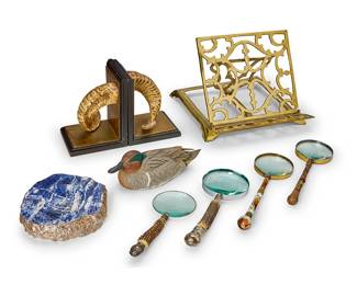 1033
A group of book and desk accessories
20th century
Comprising an ANNA New York sodalite and silver bowl (1.5" H x 8" Dia.), a pair of composite, brass, and wood bookends in the form of ram's horns (Each: 8" H x 6.25" W x 6" D), an adjustable brass book stand (10.5" H x 13.5" W x 13.5" D), and four magnifying glasses, together with a Green-Wing Teal duck decoy signed by Leo McIntosh Jr.
9 pieces
Estimate: $300 - $500