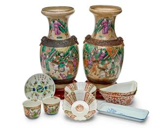 1087
A group of East Asian porcelain vessels
20th century
Each vase with stamped chop mark to underside
Comprising a pair of Chinese Nanjing porcelain vases, each decorated with figures and horses on a beige craquelure ground, the body surrounded by two brown bands, the upper band with lion's head ring handles, each set with a wood stand; and a group of vessels including a rectangular dish, a pair of five-sided dishes, a set of five Japanese scalloped bowls, a pair of tea bowls, and a small plate
13 pieces
Each vase: 17.75" H x 9" Dia.; Each larger bowl: 1.75" H x 6.25" Dia.
Estimate: $200 - $300