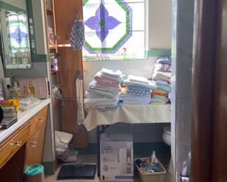 An abundance of towels and product throughout this bathroom BUT check out the stained-glass art in the window
