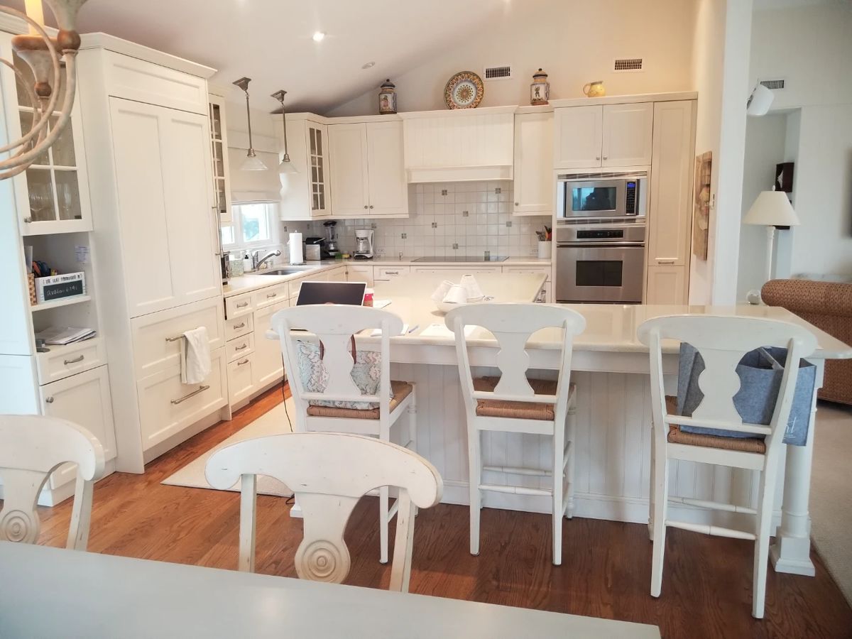 Gorgeous white L-shaped custom kitchen with ample Brookhaven cabinetry and an L-shaped island