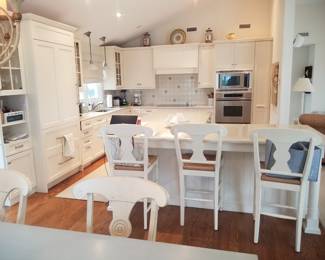 Gorgeous white L-shaped custom kitchen with ample Brookhaven cabinetry and an L-shaped island