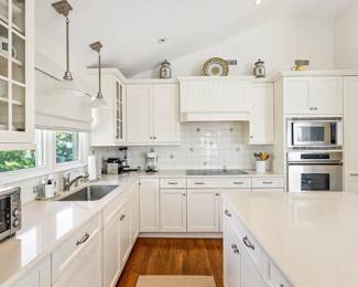 Gorgeous white L-shaped custom kitchen with ample Brookhaven cabinetry and an L-shaped island