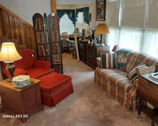 red arm chair with ottoman, side table, LaZBoy love seat, room divider, cabinets, lamps, tea cart