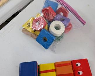 A colorful collection of durable wooden blocks in various shapes and sizes, with some featuring holes. Excellent for stacking, sorting, building, and developing fine motor skills and spatial awareness.